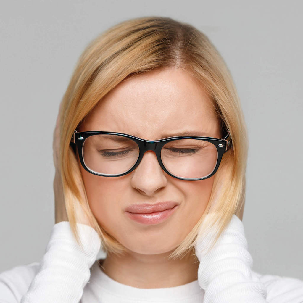 Darstellung einer Frau mit schmerzverzerrtem Gesicht, die sich die Ohren zu hält